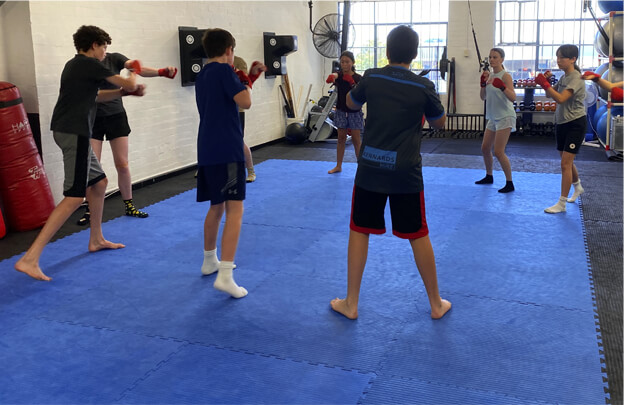 Boxing camp with teens in a circle practicing boxing drills